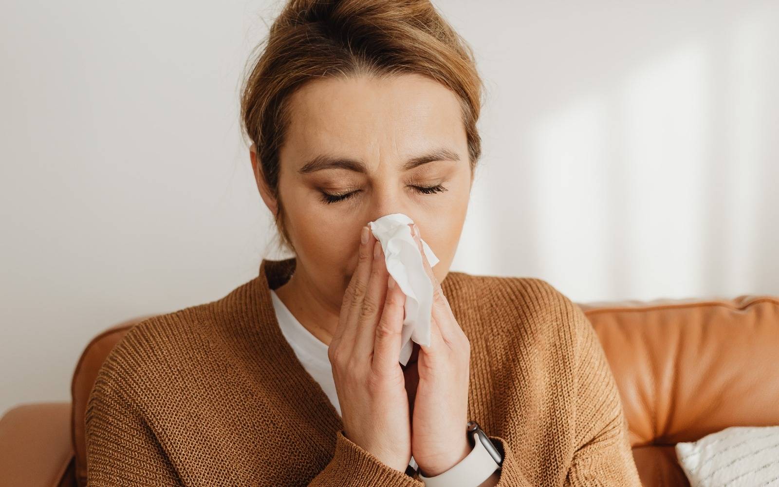 Eine Frau putzt sich die Nase.