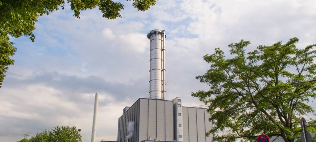 Kleine Industrie-Anlage mit Schornstein im Grünen vor locker bewölktem Himmel