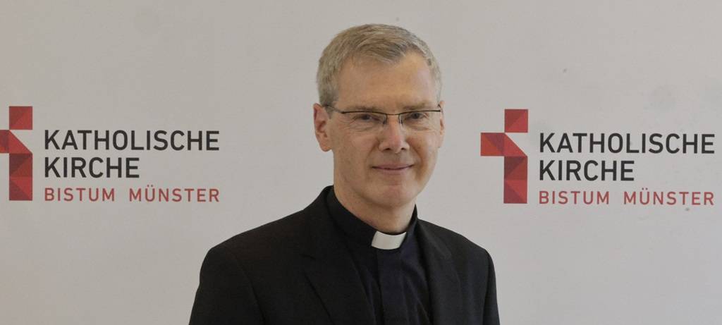 Münsters neuer Bischof Heiner Wilmer vor einer Medienwand mit dem Logo des Bistums Münster.